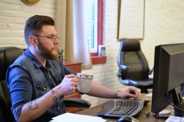 Millennial caucasian male man with beard glasses & tattoo in a modern loft office typing on keyboard
